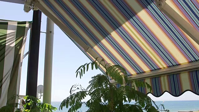 阳台与可伸缩的条纹遮阳篷与海景视频素材