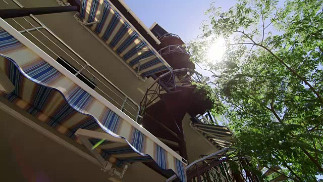 夏季酒店外部有可伸缩的条纹遮阳篷和螺旋楼梯视频素材