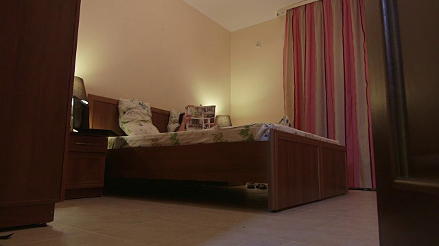 透过开着的客房门可以看到房间里的女人躺在床上看杂志视频下载