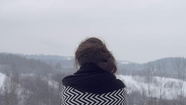 年轻的黑发女孩看着冬天的山，后视镜。视频素材