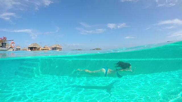 慢镜头水下:女人在美丽的豪华无限游泳池跳水视频素材