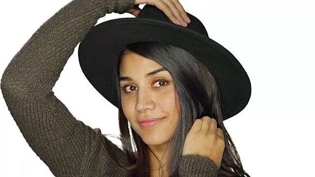 美丽的年轻女子戴着一顶帽子，并有乐趣，在一个白色的工作室背景视频下载