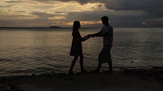 海滩上一对情侣的落日剪影视频素材