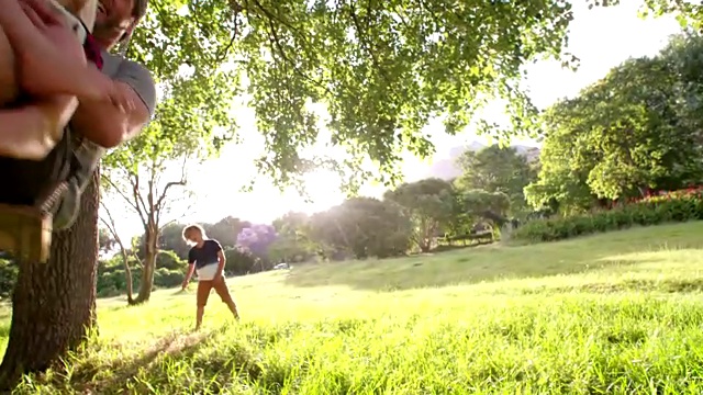 父亲和他笑着的儿子在秋千上享受夏天的日落视频素材