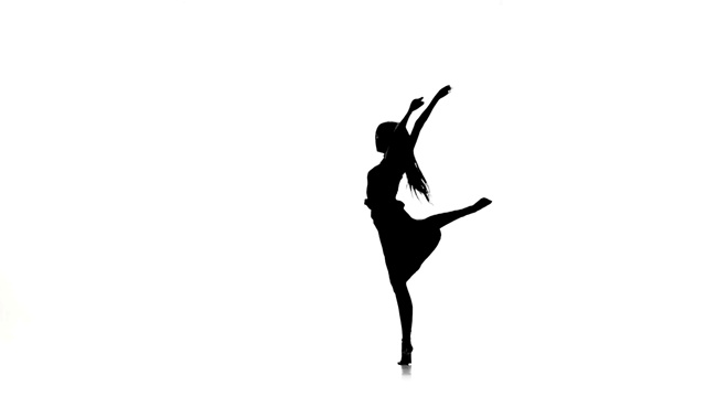 苗条的女舞者跳着现代舞，转身，上白，剪影，慢动作视频素材