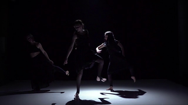 继续三位舞者在黑色、阴影、慢动作的黑暗中优雅的现代舞视频下载