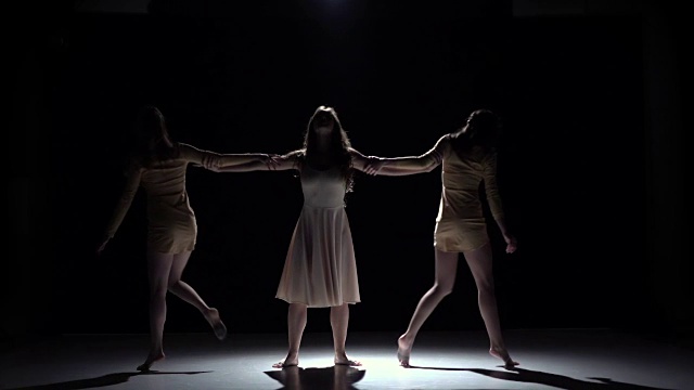 继续三位身着白衣少女的现代舞，在黑色，阴影，慢动作视频下载