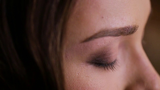 近距离的专业化妆师做一个年轻美丽的女士化妆。视频下载