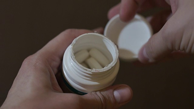 男人打开一个药瓶，吃一粒药丸视频下载