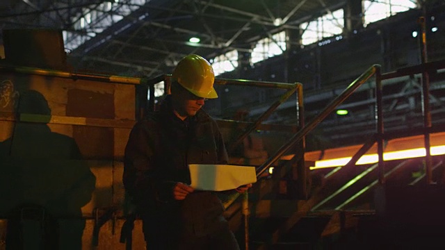 安全帽技术员在铸造厂中行走。工业环境。视频下载