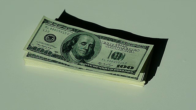手移堆在一百美元钞票上的特写镜头视频素材