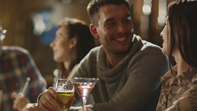 朋友们开怀大笑，喝着啤酒和鸡尾酒，一起在酒吧度过美好时光。视频素材
