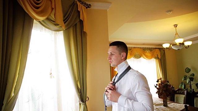 一位年轻成功的商人穿着白衬衫在他下榻的饭店的会议销售会上准备参加一个商务会议。视频下载