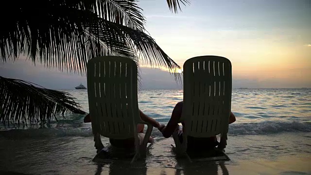 一对情侣在热带海滩上欣赏日落，接吻。缓慢的运动。视频素材