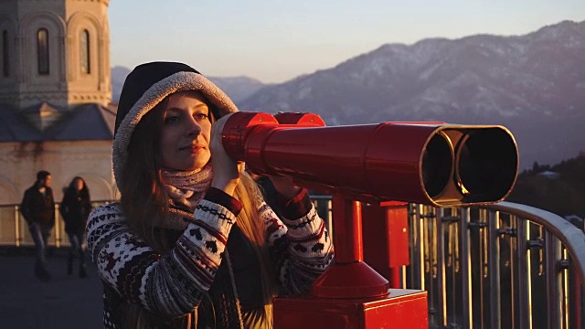 游客通过投币双筒望远镜看城市日落，中镜头视频下载