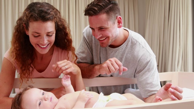 快乐的父母和婴儿床里可爱的儿子玩耍视频素材