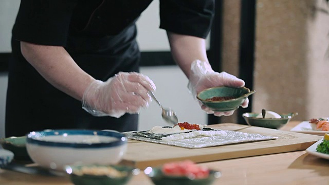 寿司师傅在寿司卷中加入鱼子酱视频素材