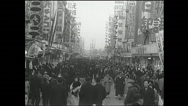 行人拥挤的市场街道;战后日本的市场上挂着电影海报。视频素材