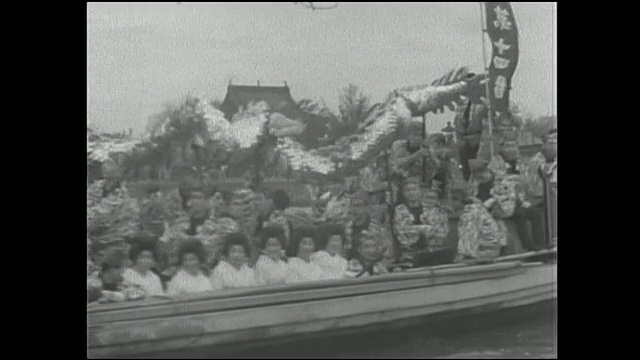 乘客坐在一条纸龙下面，他们的船沿着Sumida河漂流。视频素材