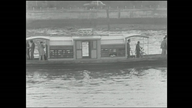 一艘筑田渡船拖着一艘客筏驶近住田河的海岸线。视频素材