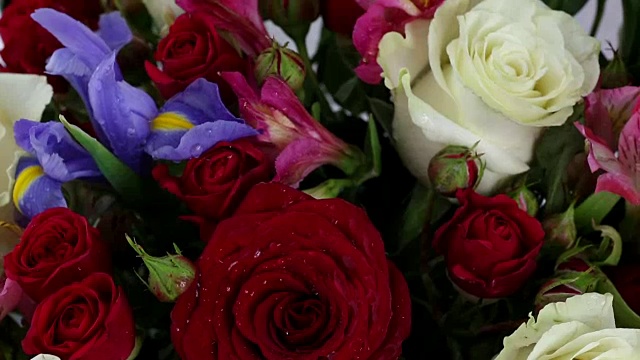 美丽的玫瑰花束，蝴蝶花和紫花快速旋转视频下载