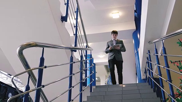 一个拿着平板电脑走下楼梯的商人视频素材
