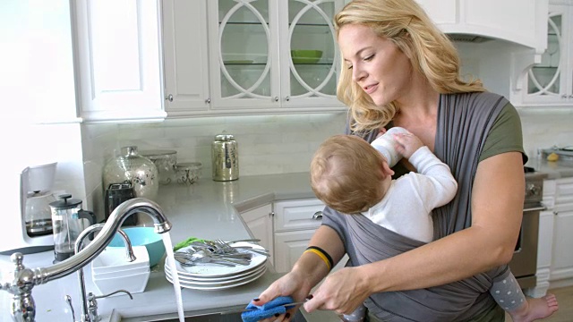 忙碌的母亲与婴儿在吊带在家，慢镜头视频素材