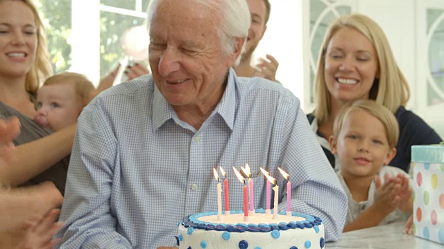 爷爷在生日蛋糕上吹蜡烛，慢镜头视频素材