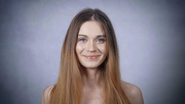 灰色背景上美丽微笑的女人肖像。视频素材
