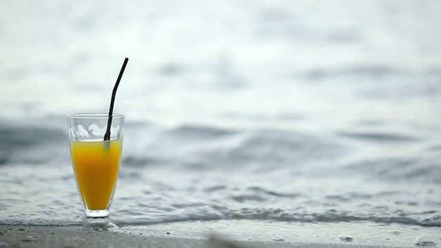 在海滩上喝着鸡尾酒，海浪冲刷着海岸视频素材