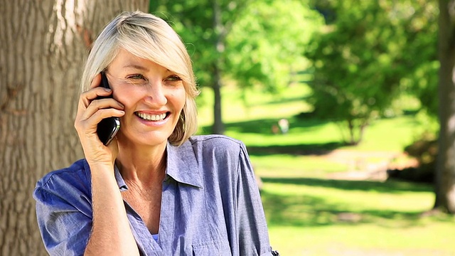 在公园里用手机聊天的快乐女人视频素材