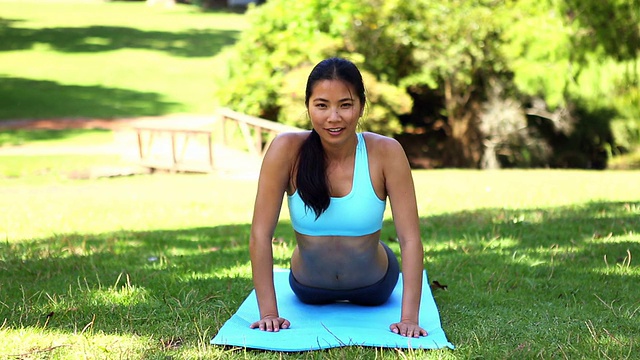 健美的亚洲女孩在公园里做瑜伽视频素材