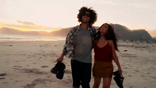 一对时髦的年轻夫妇在海滩上浪漫地散步视频素材