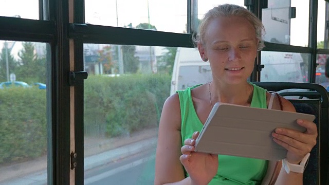 微笑的女人在公共汽车上用平板聊天视频素材