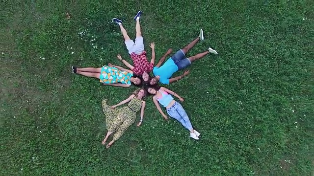 空中一群朋友组成一个星星的形状躺在草地上视频下载