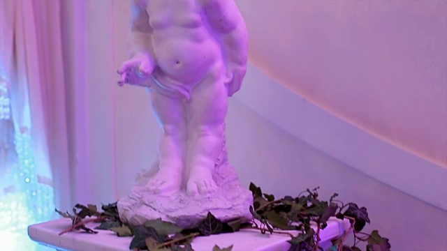 一个天使的雕像被放置在一堵紫色的墙上视频素材