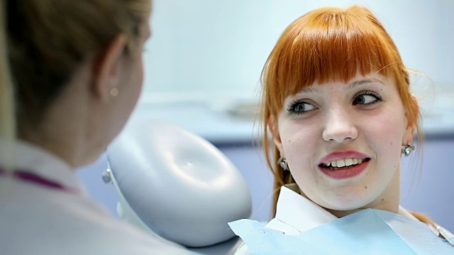 健康和牙科护理，作为牙医和医生的妇女，在专业实验室会见助理和与年轻女性病人交谈视频下载