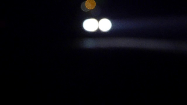 晚上开着灯的车。汽车在空旷的夜里行驶。在一片漆黑中，只能看到汽车前灯的亮光。视频素材