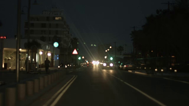 汽车在夜晚行驶在城市街道上。左手遵守交通规则。视频下载