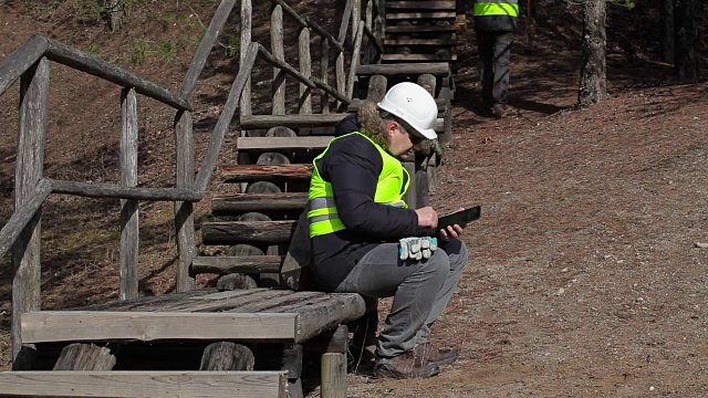 工人们拿着平板电脑和大锤靠近破碎的木轨道视频素材