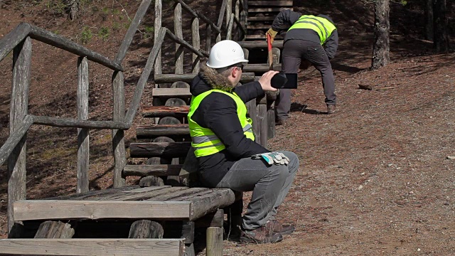 工人坐在木制轨道上使用平板电脑视频素材