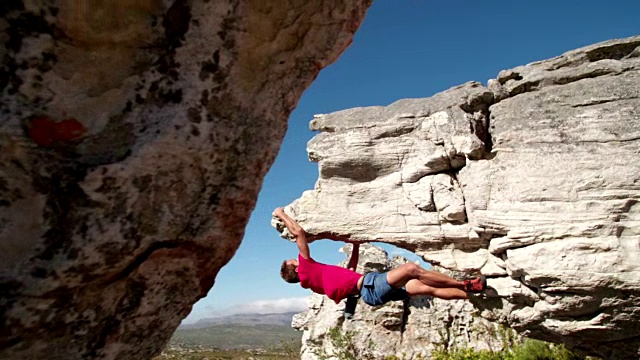 攀岩者抓住巨石，专注于路线视频素材