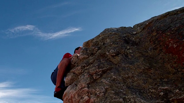 攀岩者用太阳耀斑到达巨石的顶峰视频素材
