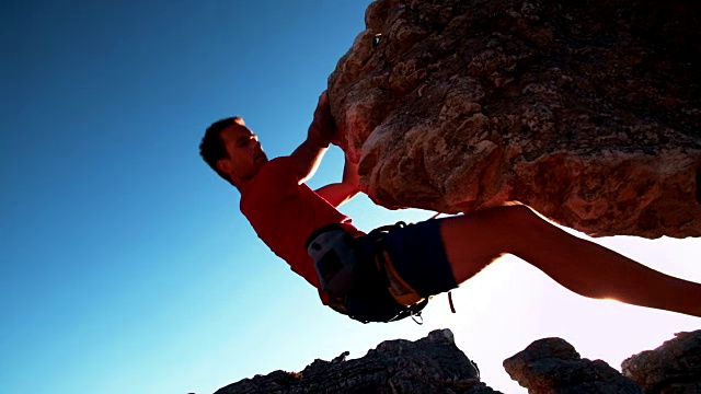 极端自由攀爬的人挂在岩石上的低角度视频素材