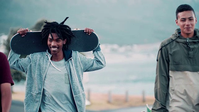 在海滩上闲逛的微笑滑冰的多民族团体视频素材