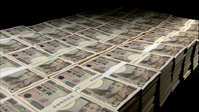 在日本东京，一盏灯照亮了黑色背景上一捆捆的一万日元钞票。视频素材