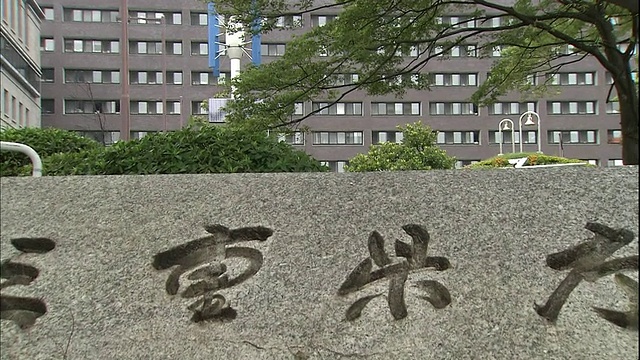 树木和灌木环绕着一个标明日本三重县政府办公室的石头标志。视频素材