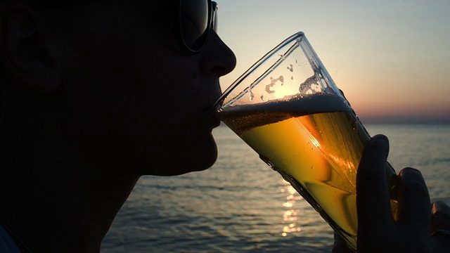日落时分在海滩上喝啤酒的女人视频素材