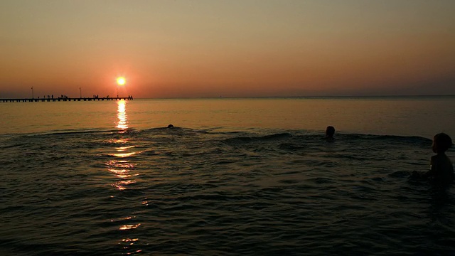 夕阳西下，一家人在海里沐浴视频素材