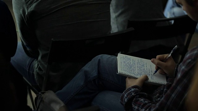 穿格子衬衫的人把笔记本放在腿上写东西视频素材